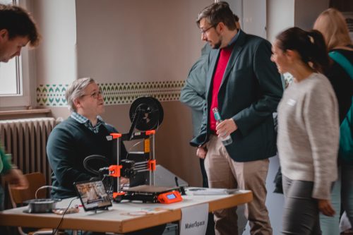 Ein weiterer Stand mit Menschen. Auf dem Tisch steht ein technisches Gerät.